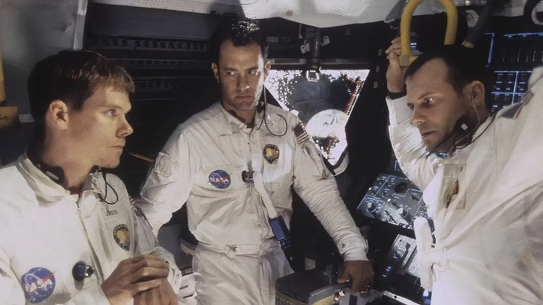 Kevin Bacon, Tom Hanks, and Bill Paxton as Jack Swigert, Jim Lovell and Fred Haise sitting together and listening through earpieces in Apollo 13 (1995)