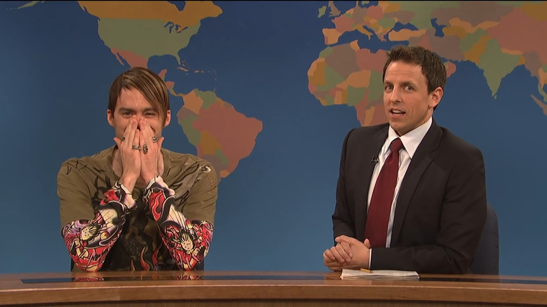 Bill Hader as Stefon with hands covering face sitting next to Seth Meyers