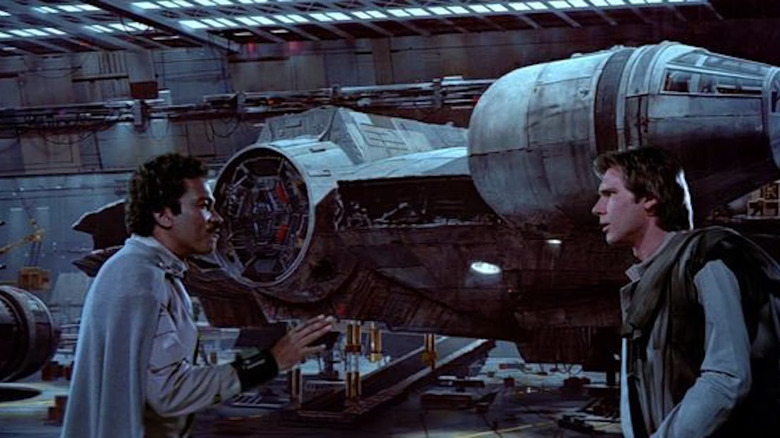 Lando and Han talking in front of the Millennium Falcon