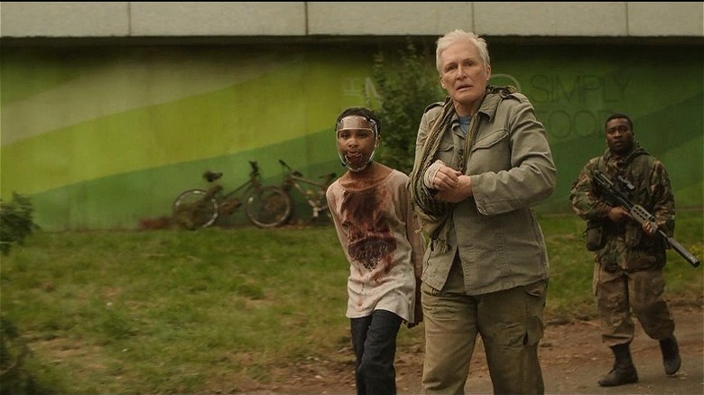 Glenn Close walking next to child with mask and bloody face and clothes in The Girl With All The Gifts