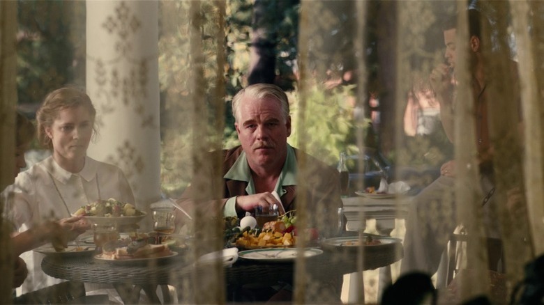 The Master's Peggy and Lancaster Dodd sitting at a table on the porch