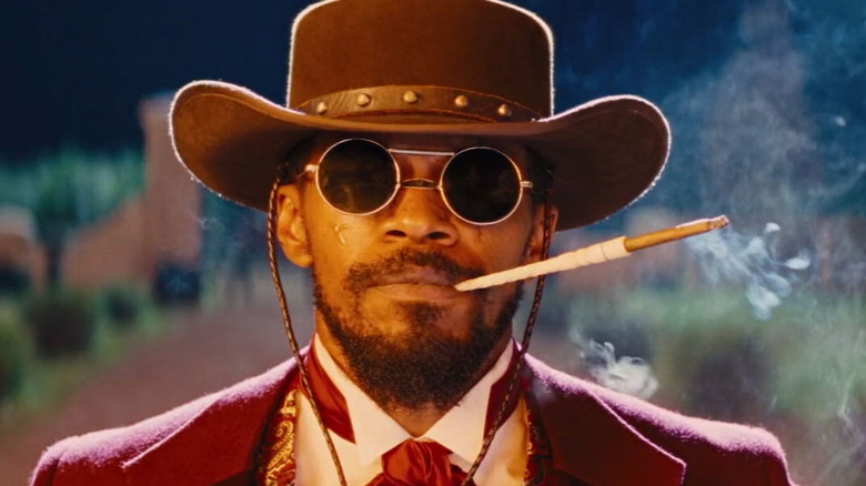 Django smoking while wearing a hat and sunglasses