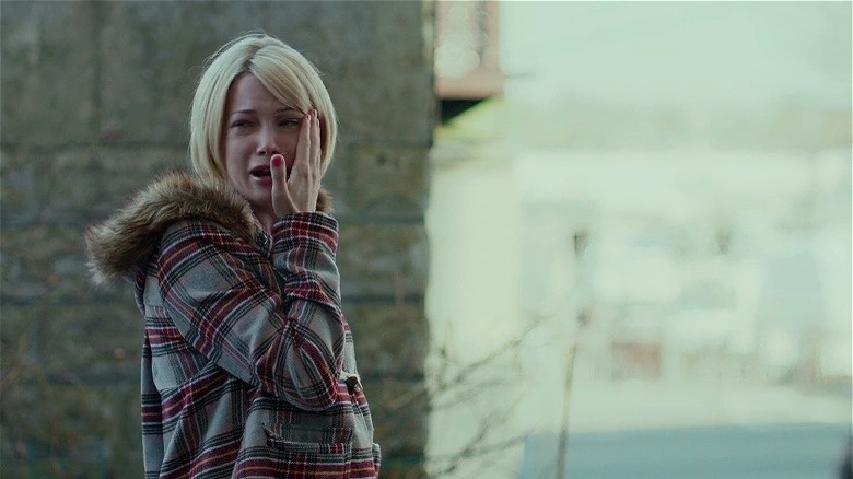 Michelle Williams outside in coat crying and putting hand to face in Manchester by the Sea