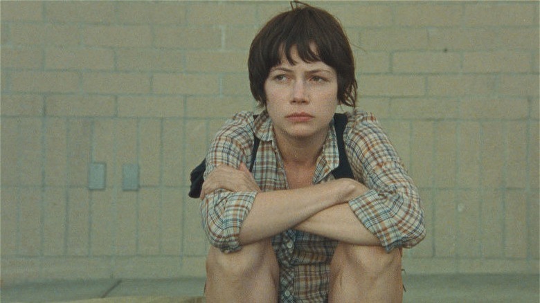 Michelle Williams with short dark hair sitting down in Wendy and Lucy