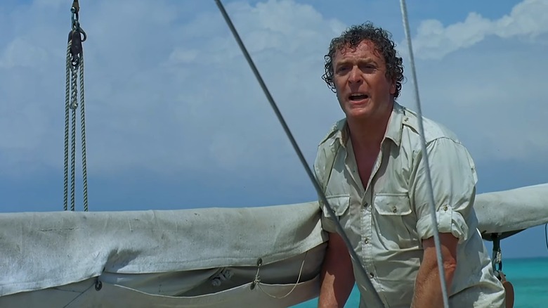 Michael Caine as Hoagie stands on a boat in Jaws: The Revenge