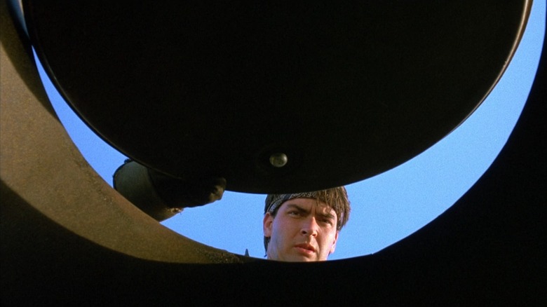 Charlie Sheen as Carl Taylor in Men at Work peering into a garbage can