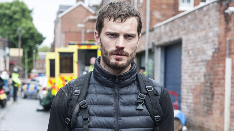 Jamie Dornan as Peter Spector, walking away from an ambulance with a bloody lip in The Fall