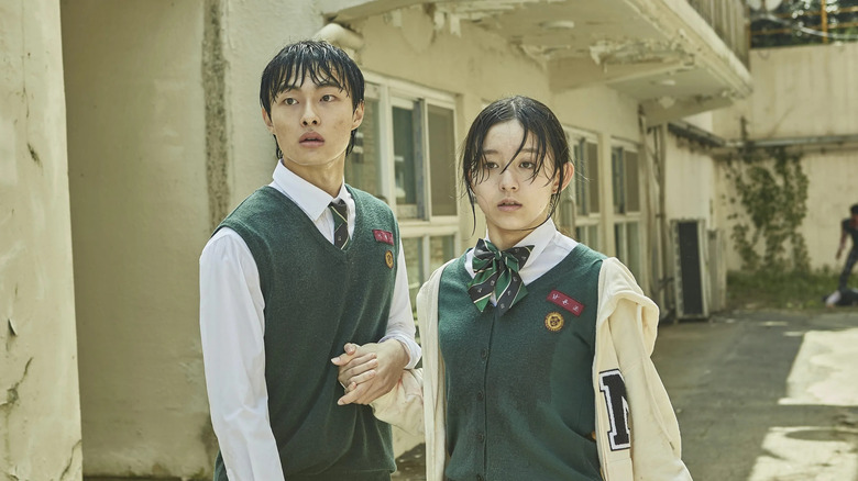 A sweaty Lee Su-hyeok (Park Solomon) and Lee Cheong-san (Yoon Chan-young) look shocked in a courtyard in All of Us Are Dead