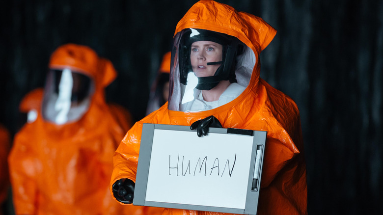 Amy Adams as Louise in Arrival, in protective suit holding board that says "human"