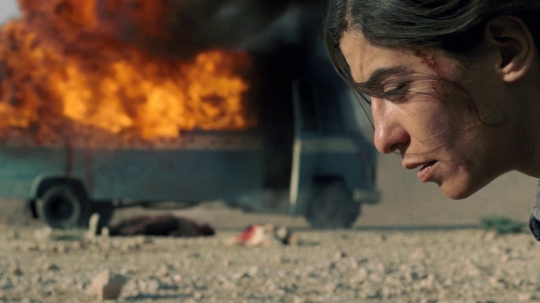 Mélissa Désormeaux-Poulin as Jeanne kneeling on ground with exploded van behind her in Incendies.