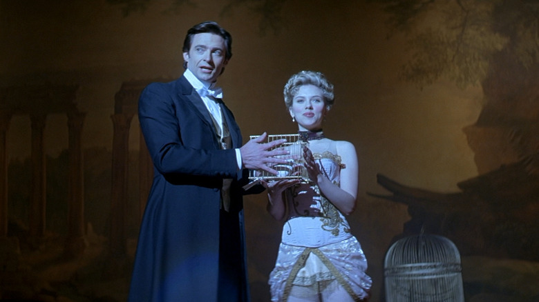 Hugh Jackman as Angier and Scarlett Johansson as Olivia on stage doing a magic trick in The Prestige.