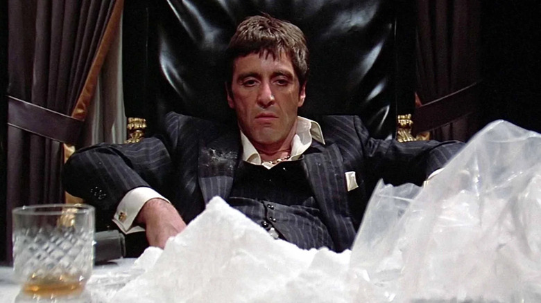 Tony Montana (Al Pacino) sits with mountains of cocaine on his desk in Scarface (1983)