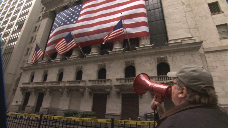 Michael Moore shouts into a megaphone toward American flags in Capitalism: A Love Story (2009)