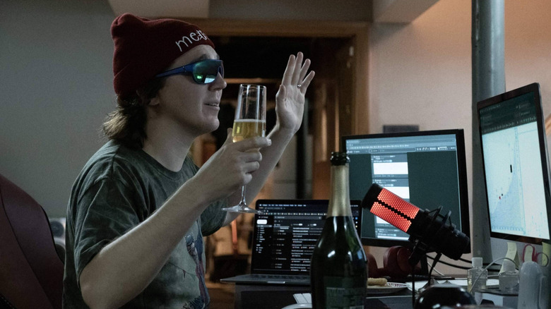 Keith Gill wearing sunglasses and drinking champagne by his computers in Dumb Money (2023)