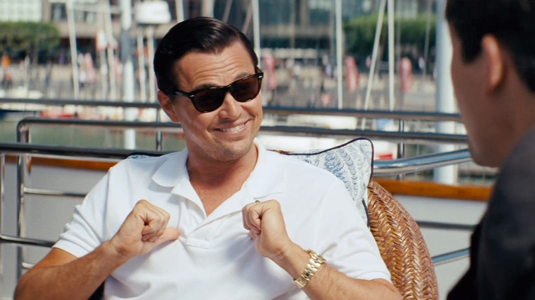 Jordan Belfort wearing sunglasses and pointing his thumbs toward him in front of FBI Agent Patrick Denham in The Wolf of Wall Street (2013)