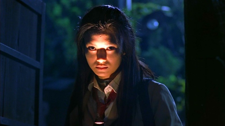 Mitsuko Souma (Kou Shibasaki) shining flashlight in her face in Battle Royale