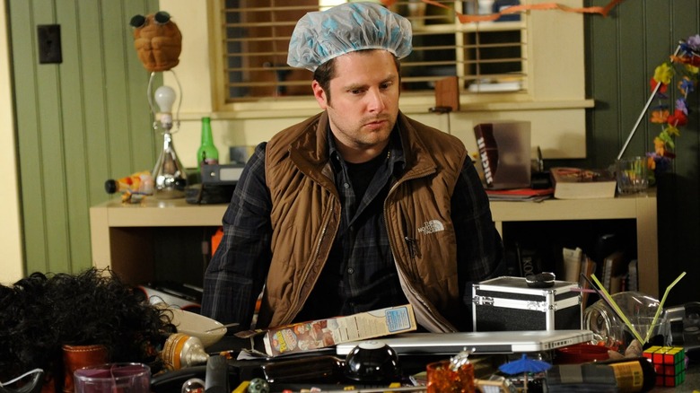 James Roday Rodriguez as Shawn, wearing a shower cap and sitting in a dirty office on Psych