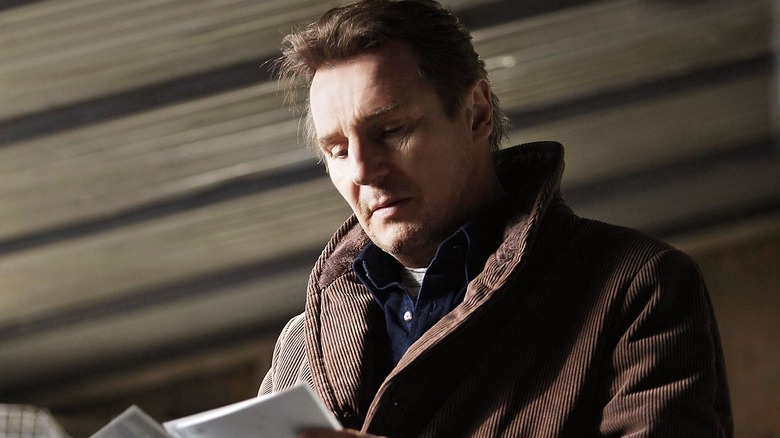 Liam Neeson as Matthew Scudder, looking down at notes in A Walk Among the Tombstones