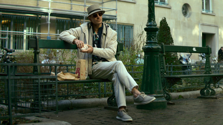 Michael Fassbender as the Killer, eating lunch on a bench in The Killer