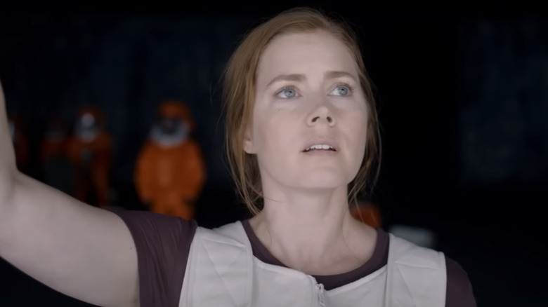 Amy Adams as Dr. Louise Banks stands in a dark room in Arrival