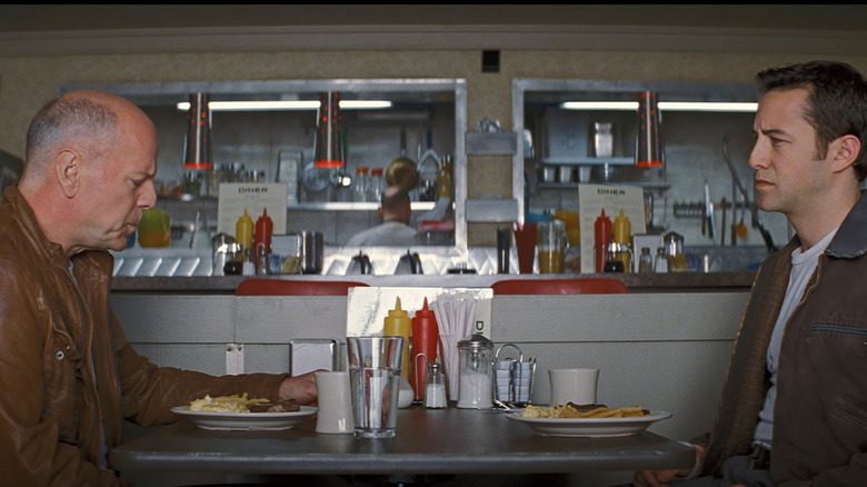 Bruce Willis as old Joe sits at a diner with Joseph Gordon-Levitt as young Joe in Looper