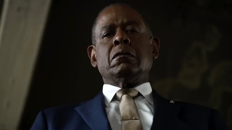 Forest Whitaker as Bumpy Johnson wearing a blue suit and looking down in Godfather of Harlem