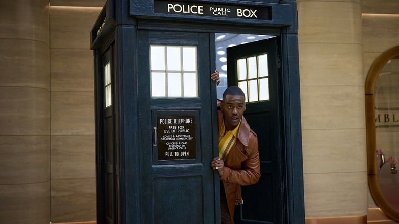 Ncuti Gatwa as Doctor Who peers out of the TARDIS which is inside a building on Doctor Who