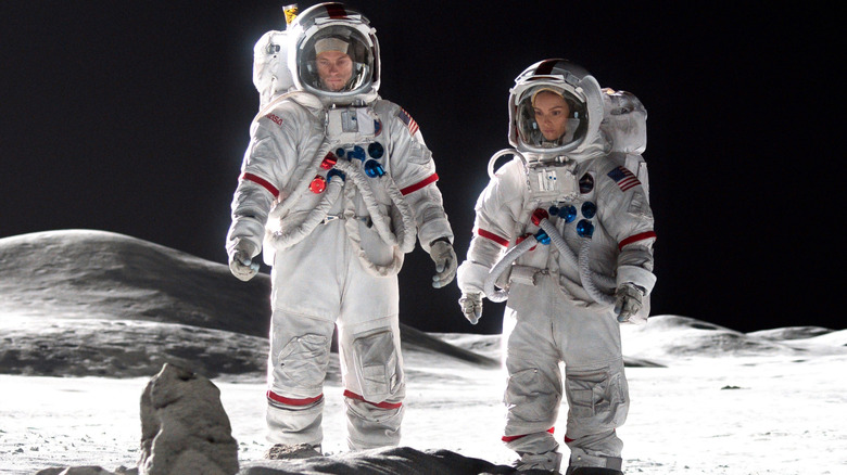 Joel Kinnaman as Edward Baldwin and Jodi Balfour as Ellen Wilson stand together in astronaut suits on the moon on For All Mankind