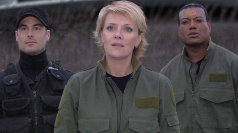 Amanda Tapping as Lieutenant Colonel Samantha Carter stands in a field with Paul Christie as Major Caffey and Christopher Judge as Teal'c on Stargate SG-1