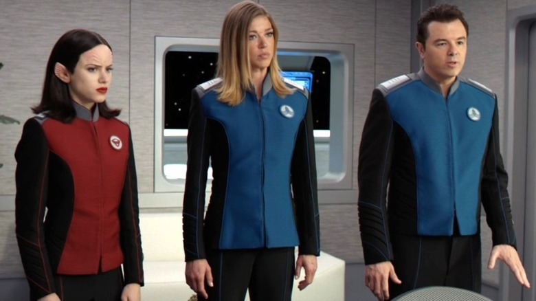 Halston Sage as Lieutenant Alara Kitan, Adrianne Palicki as Commander Kelly Grayson, and Seth MacFarlane as Ed Mercer stand together inside the USS Orville on The Orville