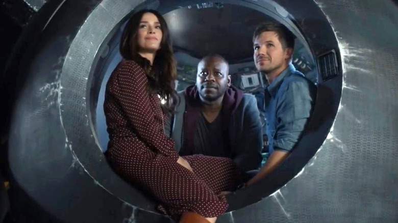 Abigail Spencer as Lucy Preston, Malcolm Barrett as Rufus Carlin, and Matt Lanter as Wyatt Logan peer out of The opening of the Life Boat on Timeless