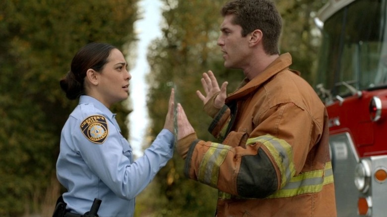 Natalie Martinez as Linda Esquivel and Josh Carter as Rusty stand across from each other as their hands touch the dome on Under the Dome