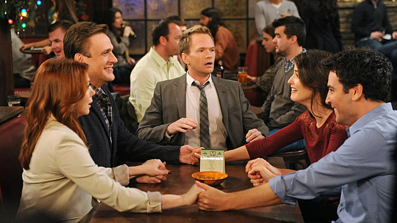 Barney (Neil Patrick Harris) looks incredulously as his friends hold hands in How I Met Your Mother