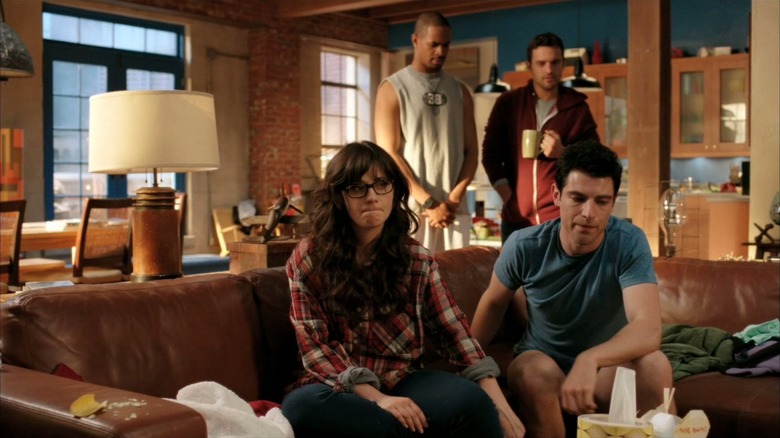 Jess (Zooey Deschanel) sits on a couch with Schmidt (Max Greenfield) in New Girl