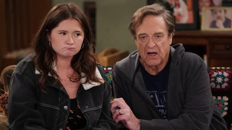 Harris (Emma Kenney) and Dan (John Goodman) sit on a couch in The Conners