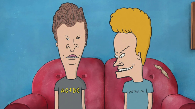 Beavis (Mike Judge) sits with Butt-head (Judge) on a worn couch on Beavis and Butt-Head