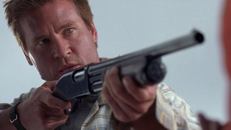 Val Kilmer holding a shotgun