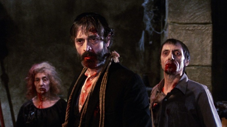 Bloody-mouthed zombies stand in a crypt