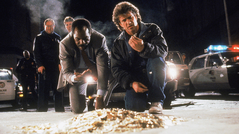 Danny Glover and Mel Gibson picking up gold coins