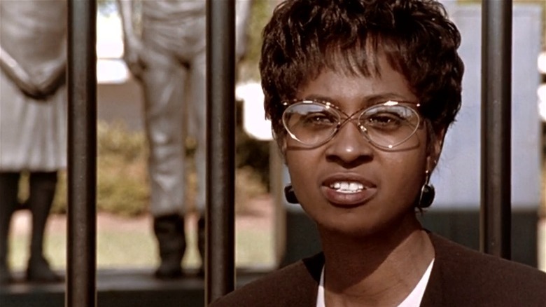 A Black woman speaks in front of a statue of children