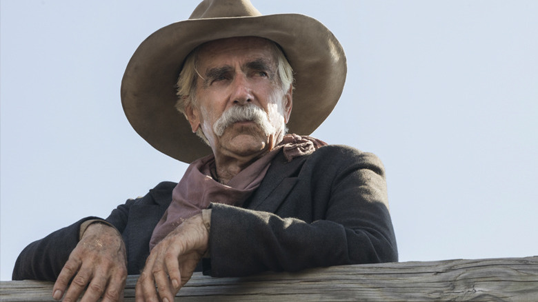 Sam Elliott leaning against a fence