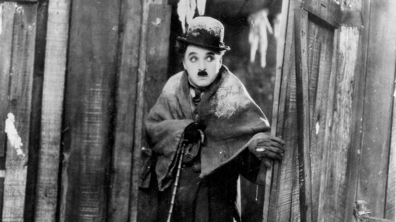 The Tramp (Charlie Chaplin) exits a cabin wearing a blanket in The Gold Rush