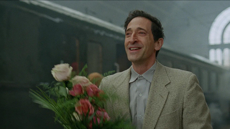 Adrien Brody holding flowers in The Brutalist