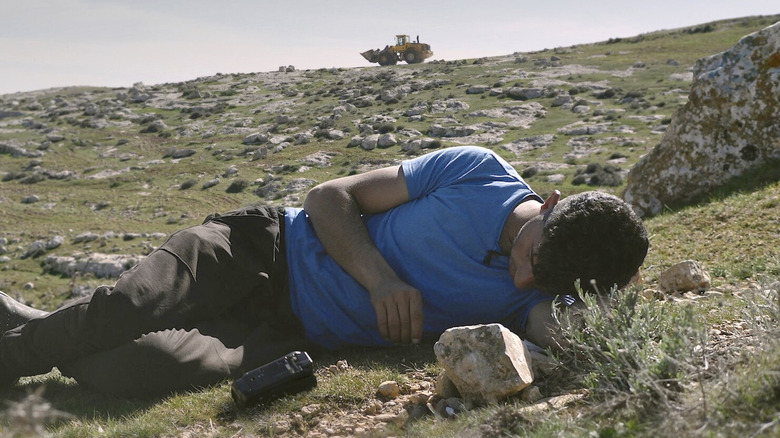 A man lays on a stone-filled hill in No Other Land