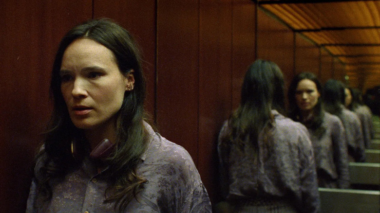 Woman in an elevator and reflections on mirror behind her in I'm Not a Robot