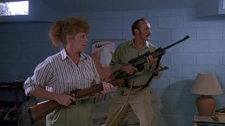 Reba McEntire as Heather Gummer and Michael Gross as Burt Gummer getting ready to kill a Graboid in their basement in Tremors