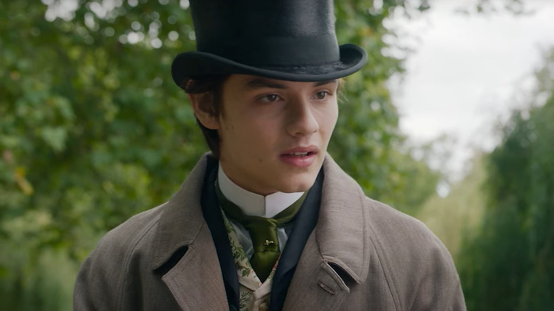 Louis Partridge as Tewkesbury standing outdoors in formal wear in Enola Holmes