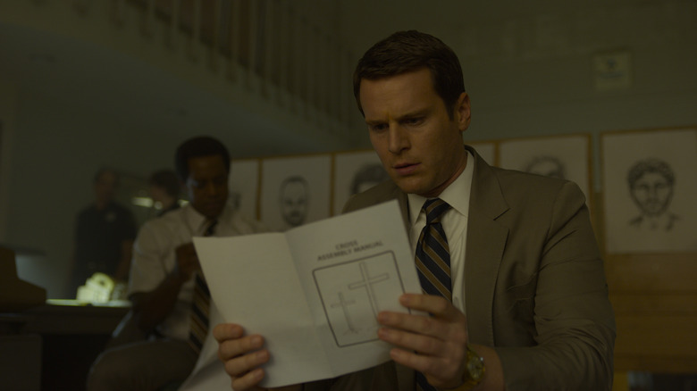 Holden intently looking at a piece of paper on Mindhunter