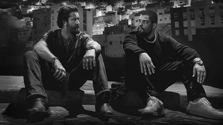 Gerard Butler's Big Nick and O'Shea Jackson Jr. as Donnie sitting on the ground on the poster for Den of Thieves 2: Pantera