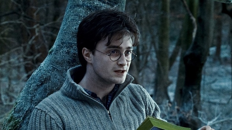 Harry reading a book against a tree in Harry Potter and the Deathly Hallows - Part 1